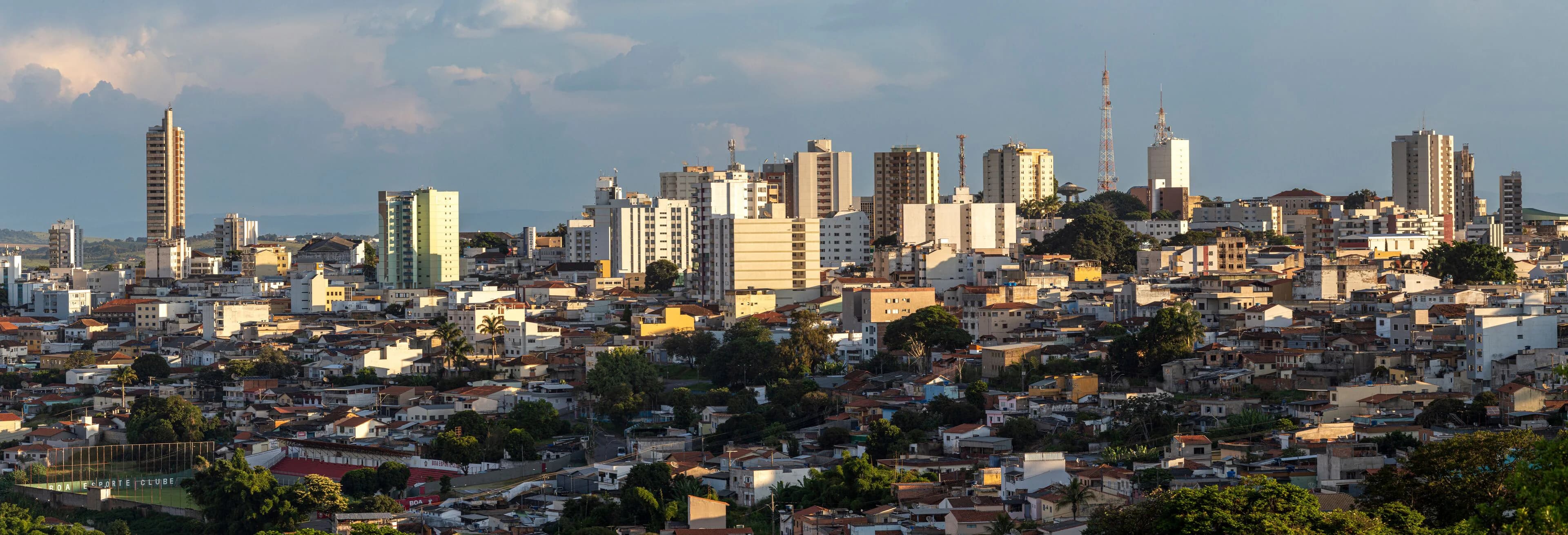 Vista panorâmica de Varginha no fim da tarde, com os prédios do centro sob um céu com nuvens
